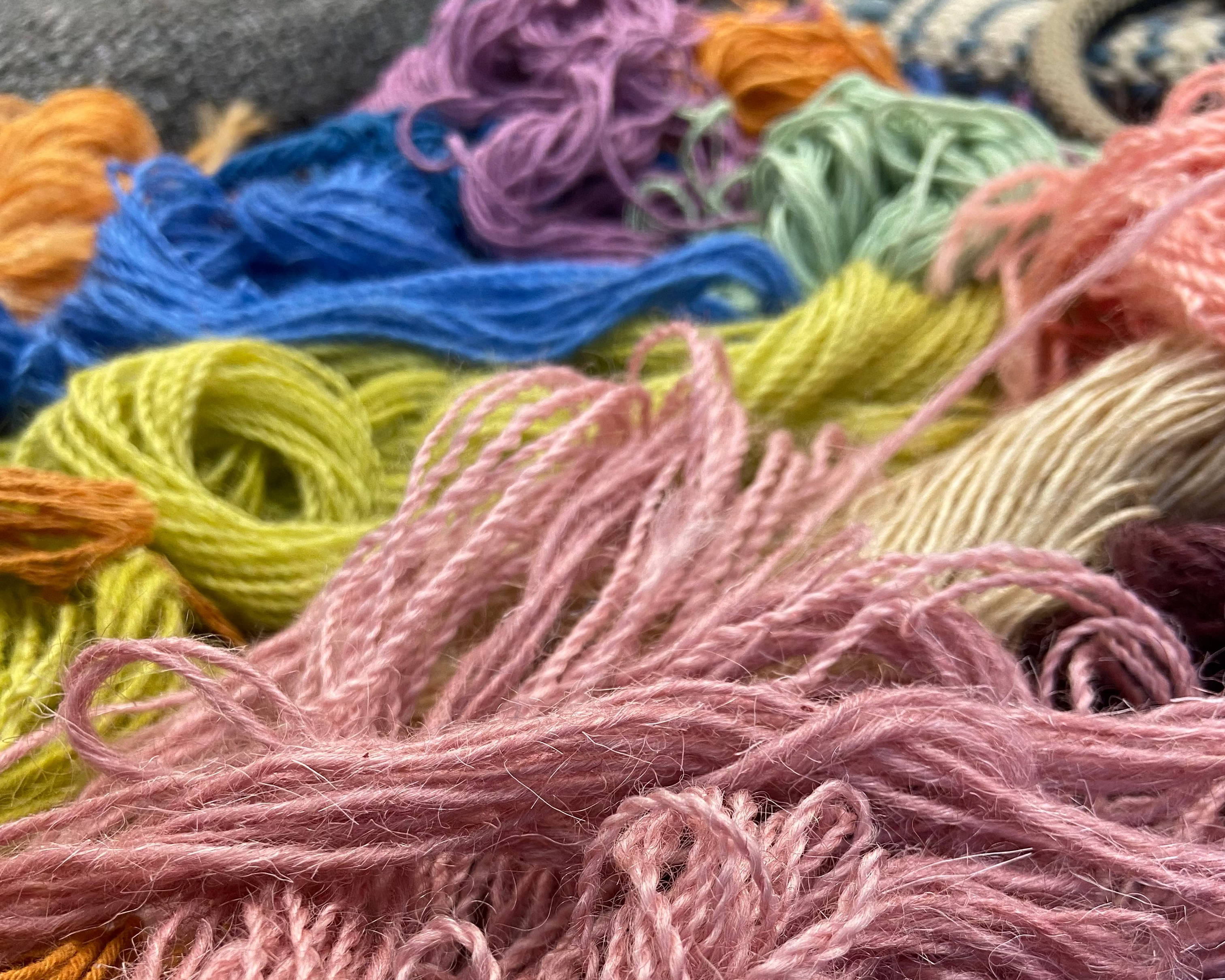 Close-up of pink yarn with other colorful yarns in the background