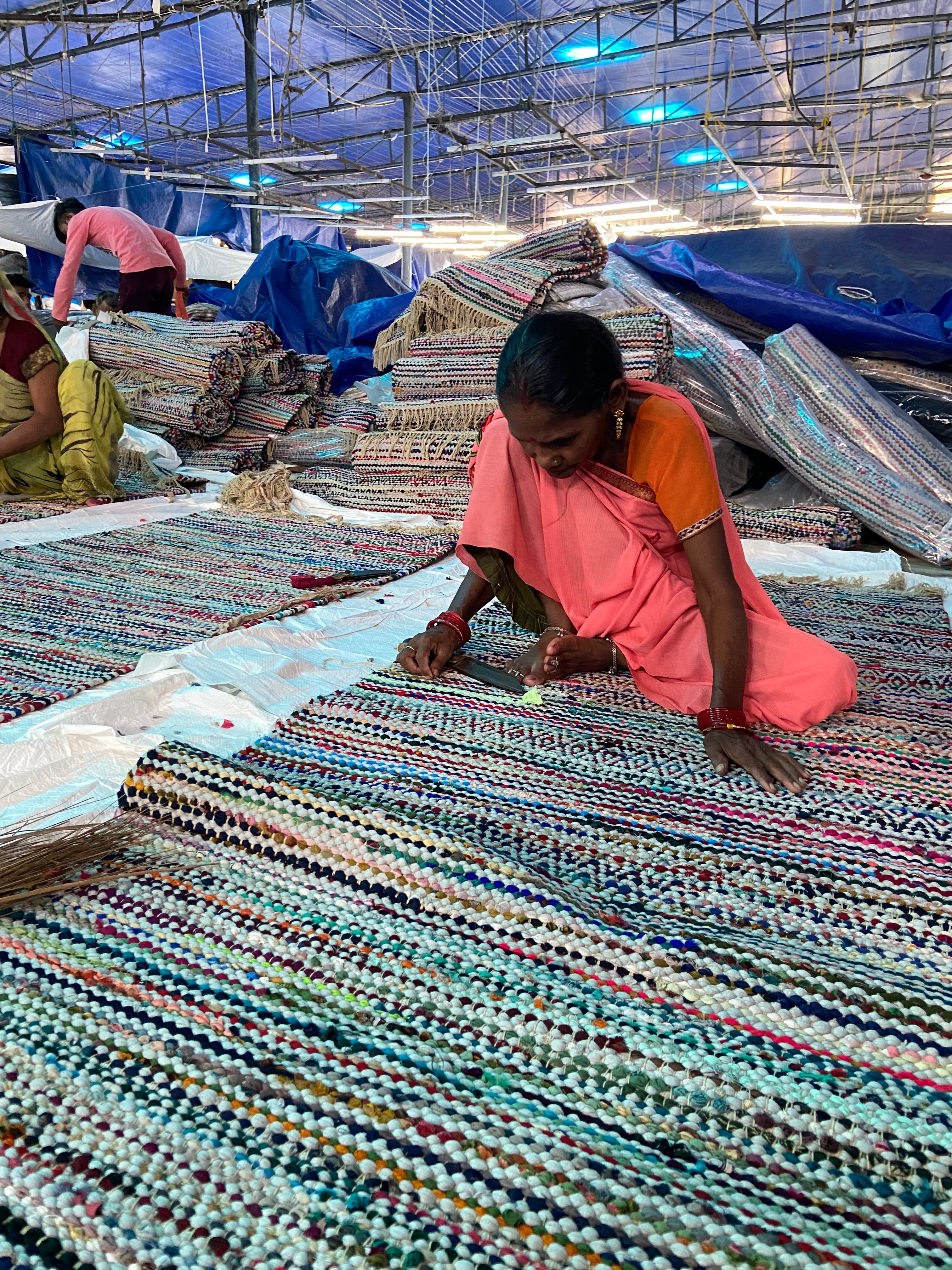 Woman working on a colorful rug in a factory setting